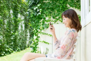 庭でスマホを使う若い女性
